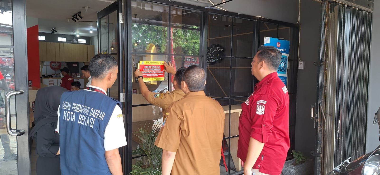 Pegawai Badan Pendapatan Daerah Kota Bekasi memasang stiker di salah satu tempat usaha di wilayah Kota Bekasi.